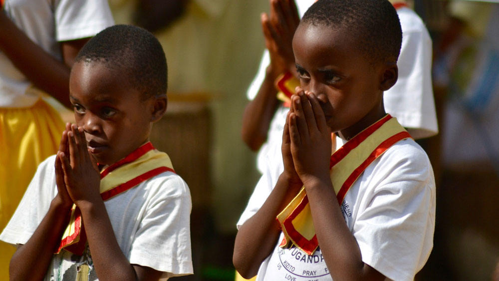 Children praying at an ordination in Uganda