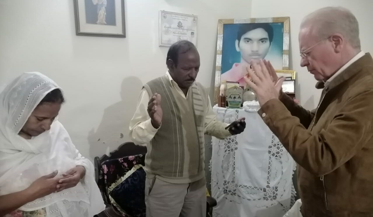 Fr Anthony praying with parents in Pakistan