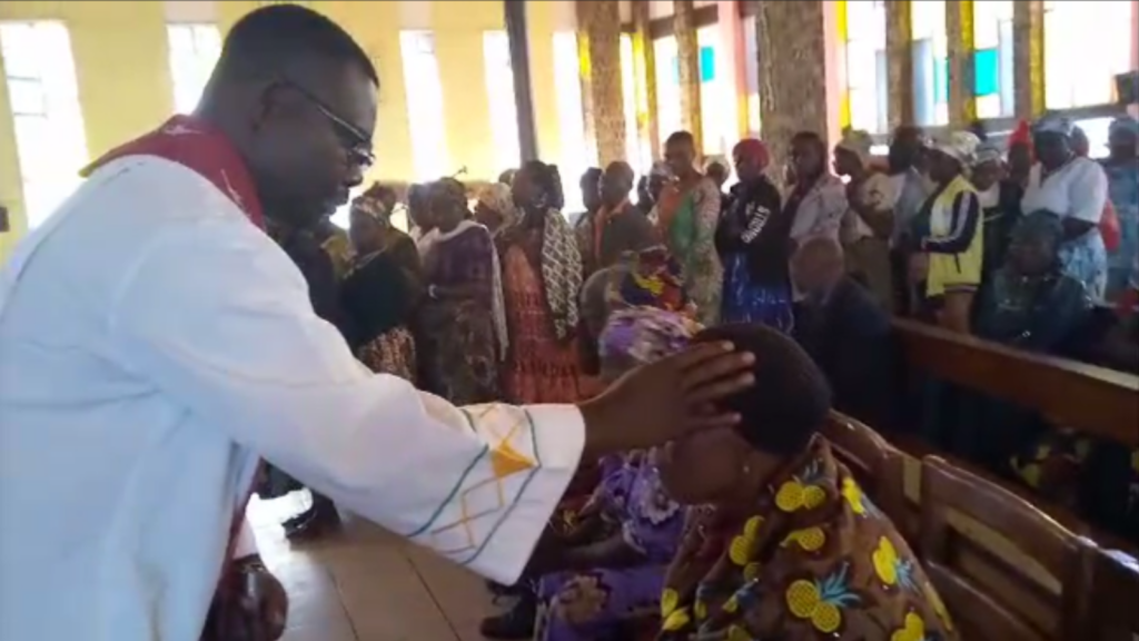 Priest blesses a sick parishioner during Mass